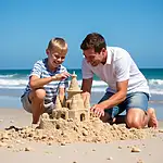 Child and adult building sandcastle on beach